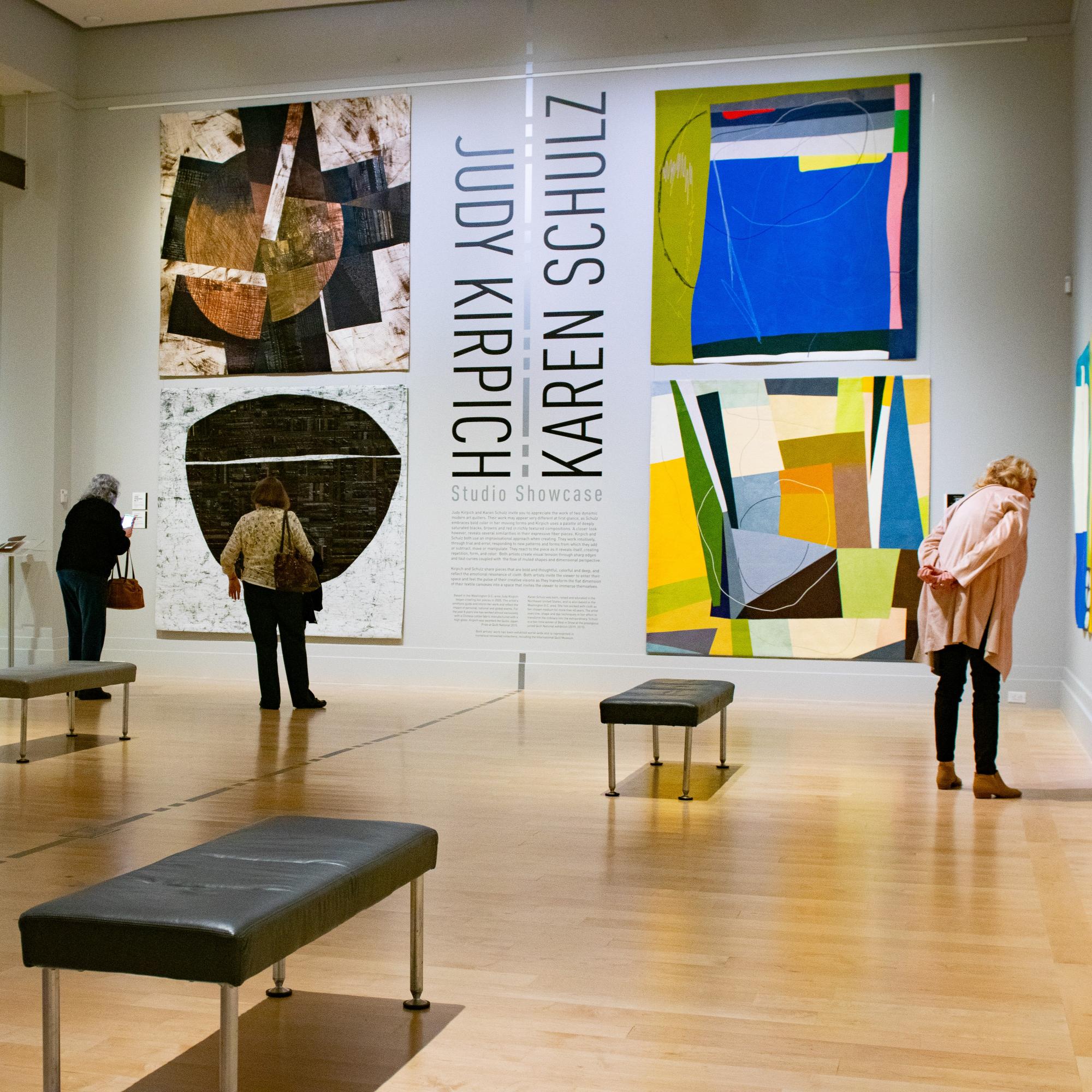 Museumgoers look at quilts the exhibition "Studio Showcase: Judy Kirpich and Karen Schulz."
