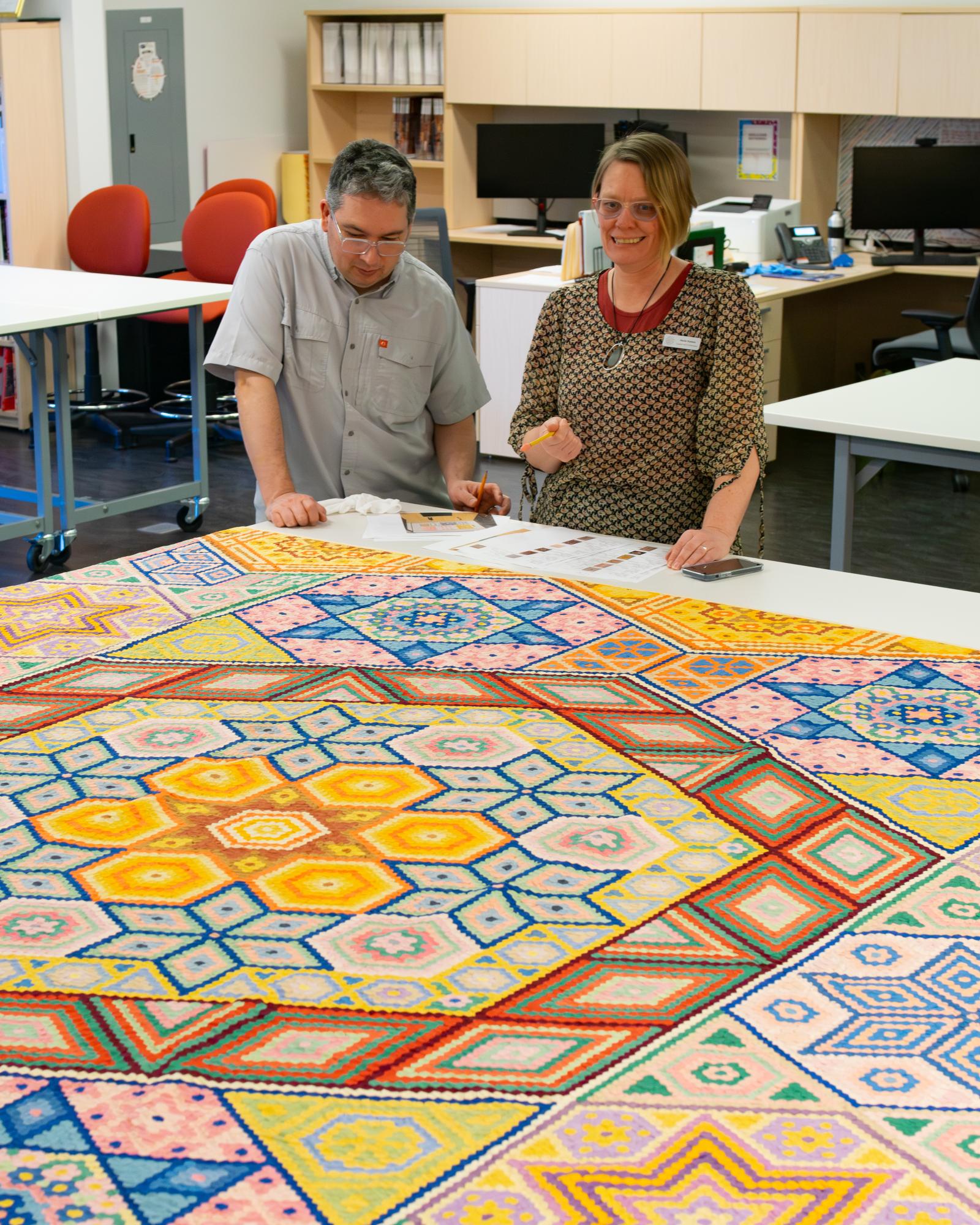 Two people look at a quilt.