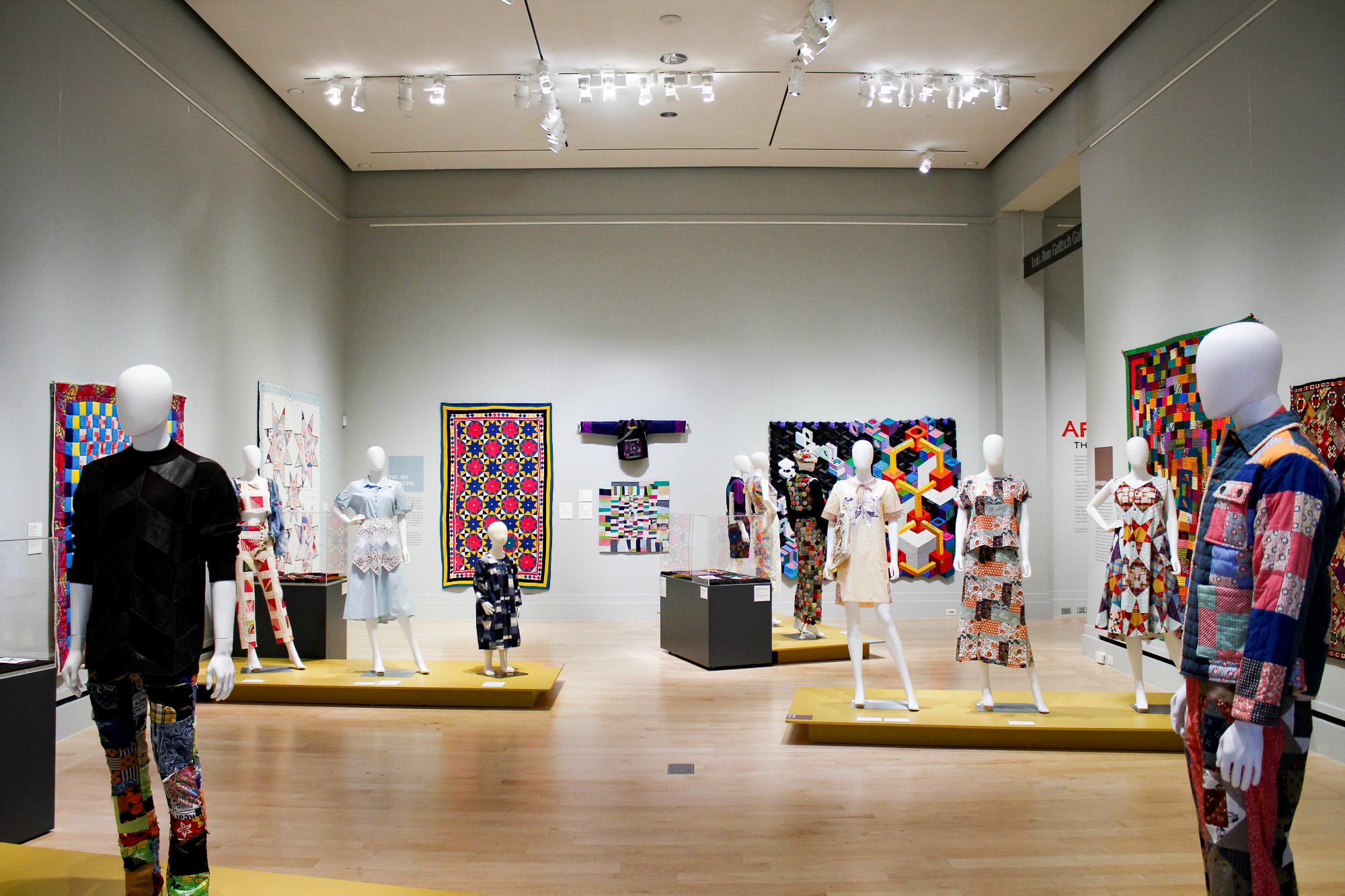 Patchwork: Quilts and Garments Across Cultures "Patchwork" exhibition with mannequins and quilts.