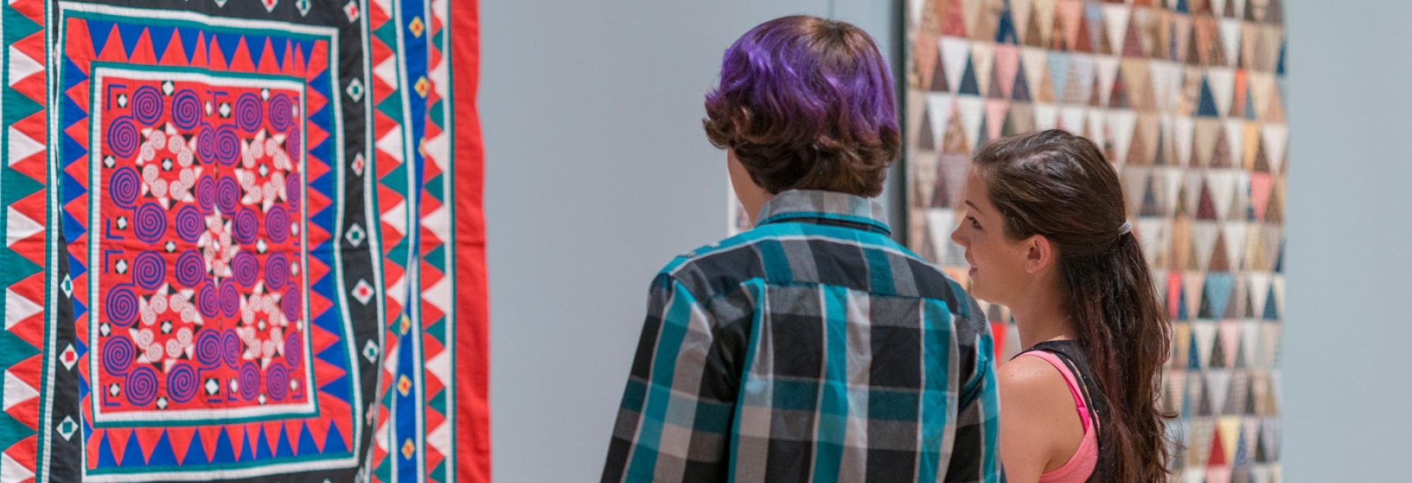 Two people look at quilts at the International Quilt Museum.