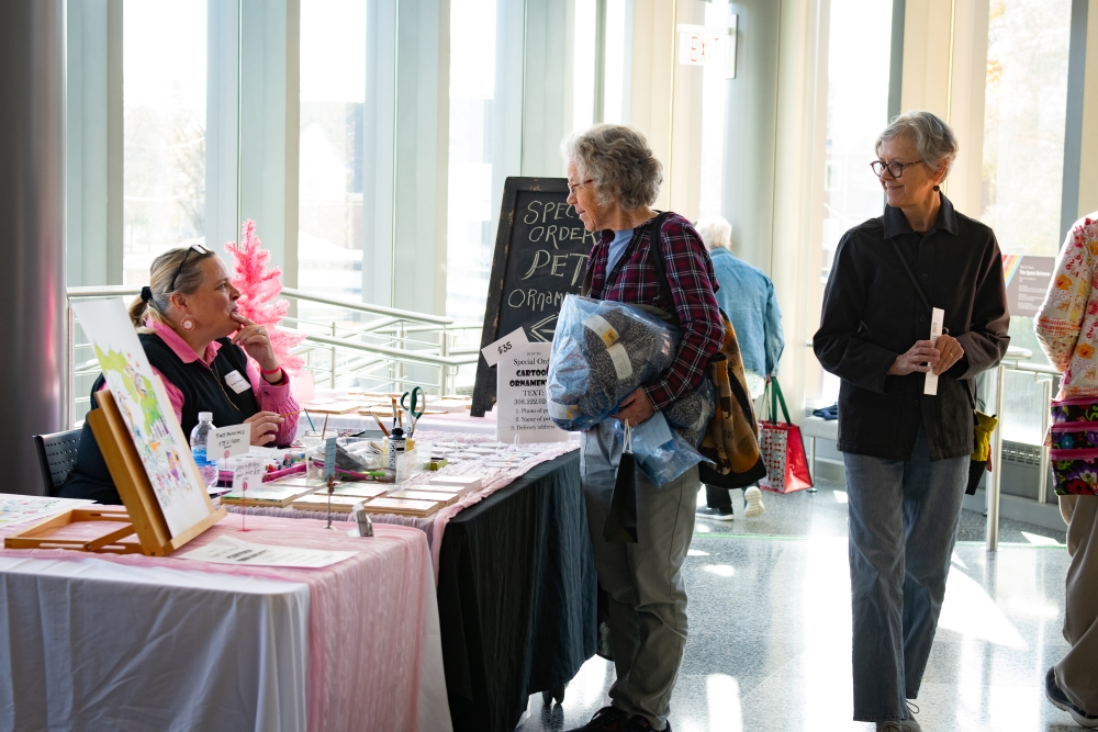 People interacting at art market.